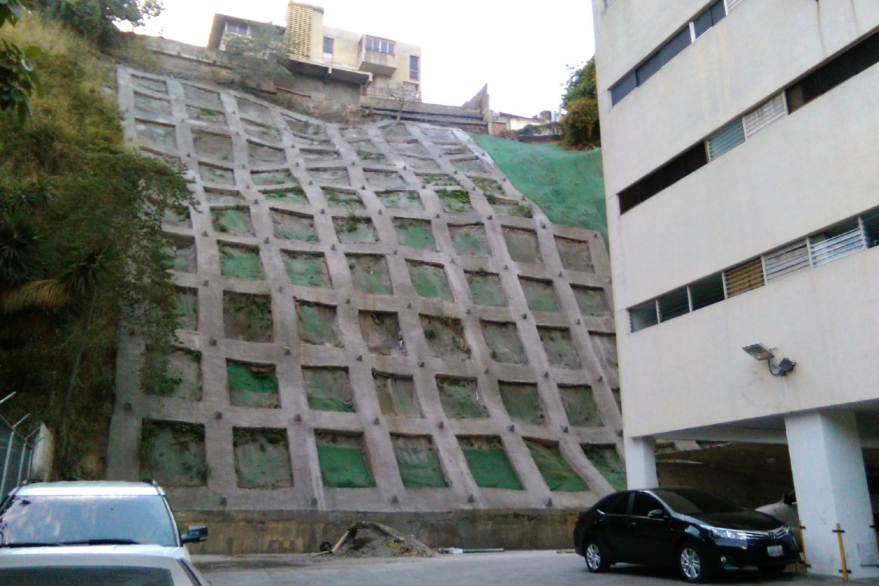 ￼Pantalla atirantada reticulada de 20 m de altura, reforzada con geomallas metálicas y geomantas verdes ECOGREEN. Residencias Icabaru. Municipio Baruta. 2014