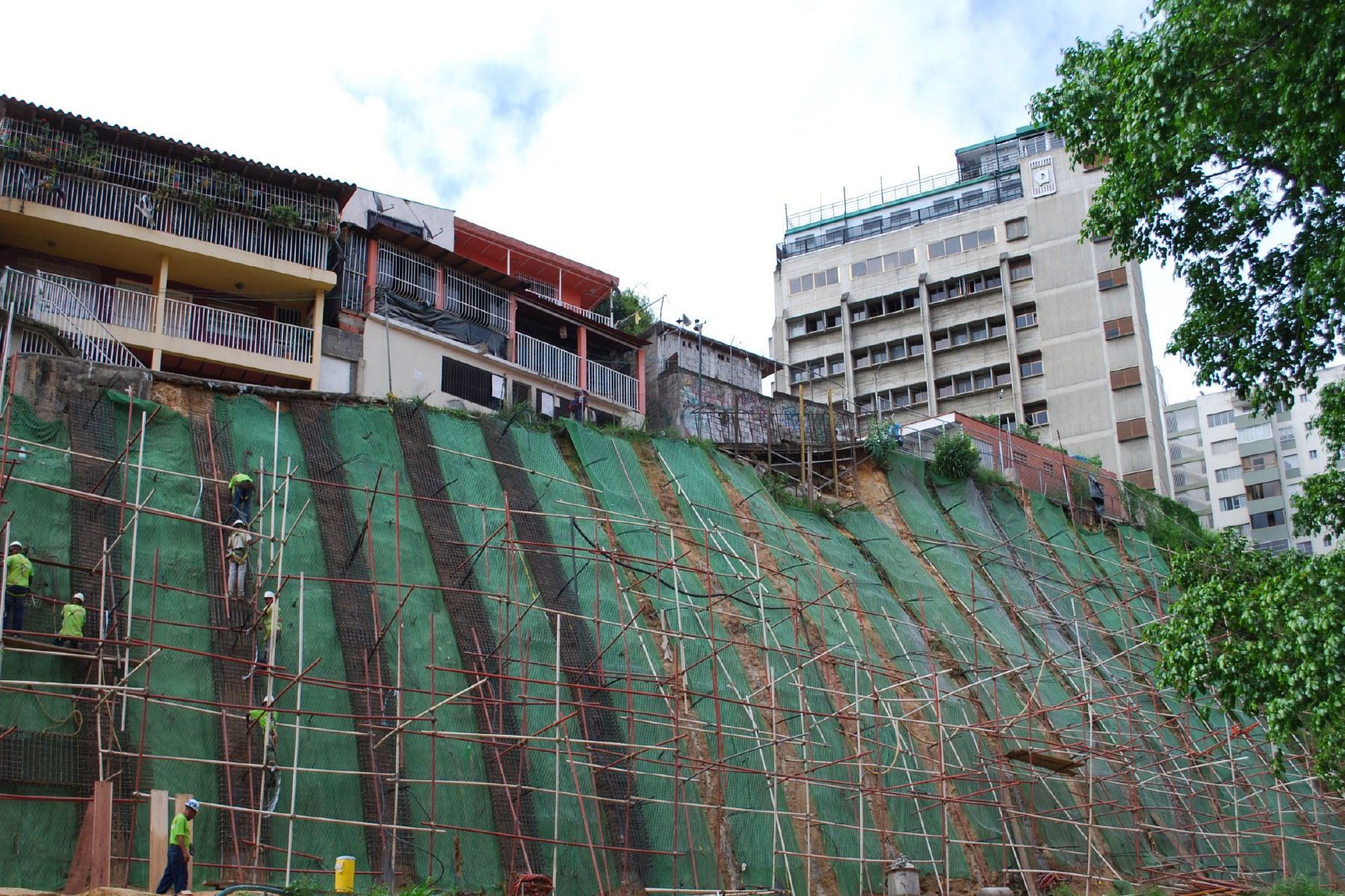 ￼Pantalla atirantada reticulada de 16 m de altura, reforzada con geomallas metálicas y geomantas verdes ECOGREEN para el control de erosión y estabilización de talud ubicado en el Barrio Santa Cruz, Municipio Baruta. 2011