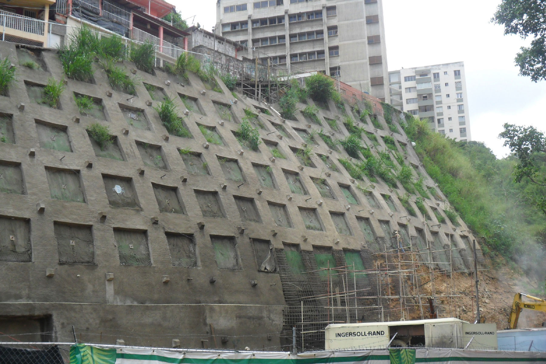 ￼Pantalla atirantada reticulada de 16 m de altura, reforzada con geomallas metálicas y geomantas verdes ECOGREEN para el control de erosión y estabilización de talud ubicado en el Barrio Santa Cruz, Municipio Baruta. 2011