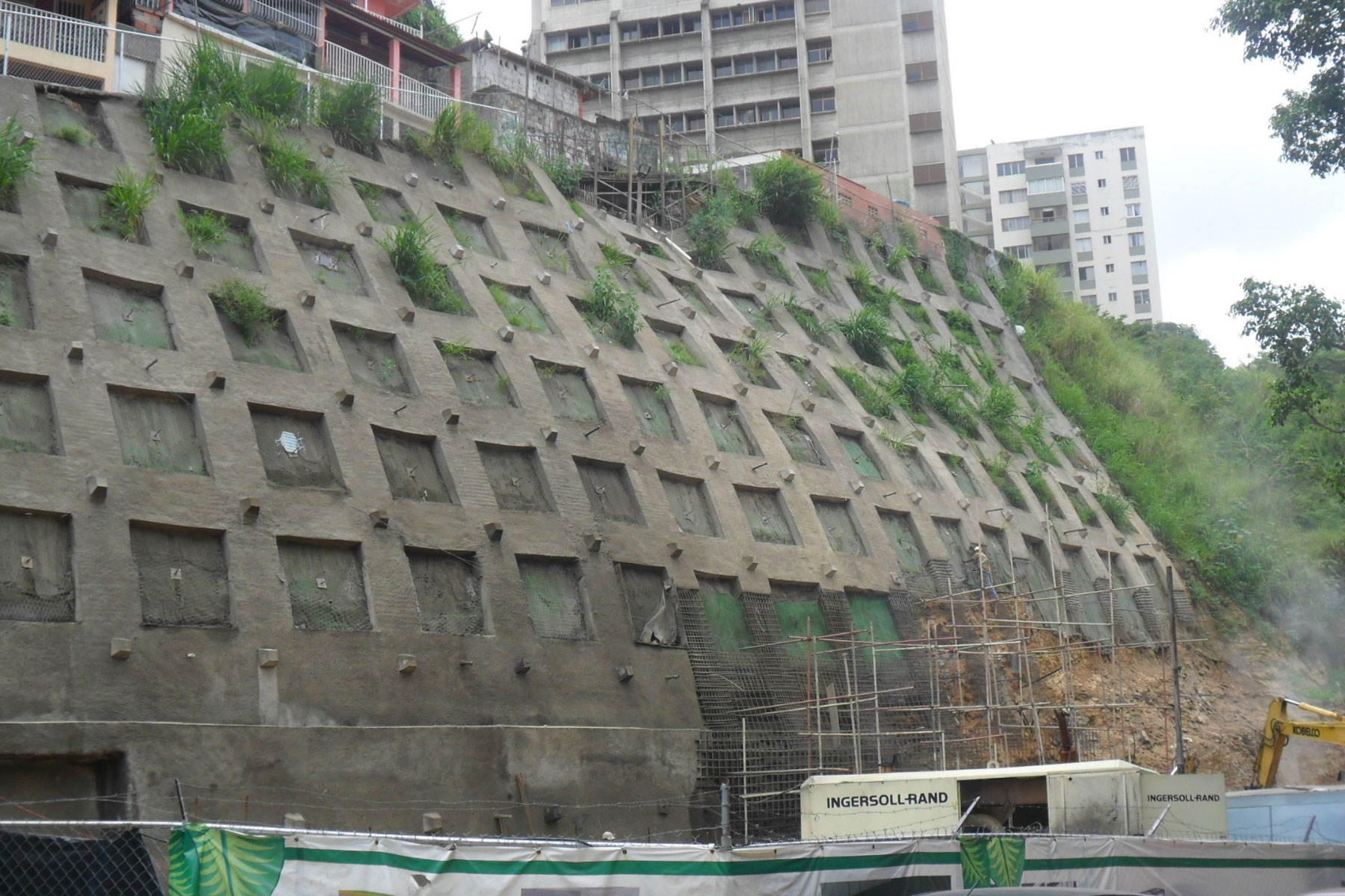 Pantalla atirantada reticulada de 16 m de altura, reforzada con geomallas metálicas y geomantas verdes ECOGREEN para el control de erosión y estabilización de talud ubicado en el Barrio Santa Cruz, Municipio Baruta. 2011 Pantalla atirantada reticulada de 16 m de altura, reforzada con geomallas metálicas y geomantas verdes ECOGREEN para el control de erosión y estabilización de talud ubicado en el Barrio Santa Cruz, Municipio Baruta. 2011